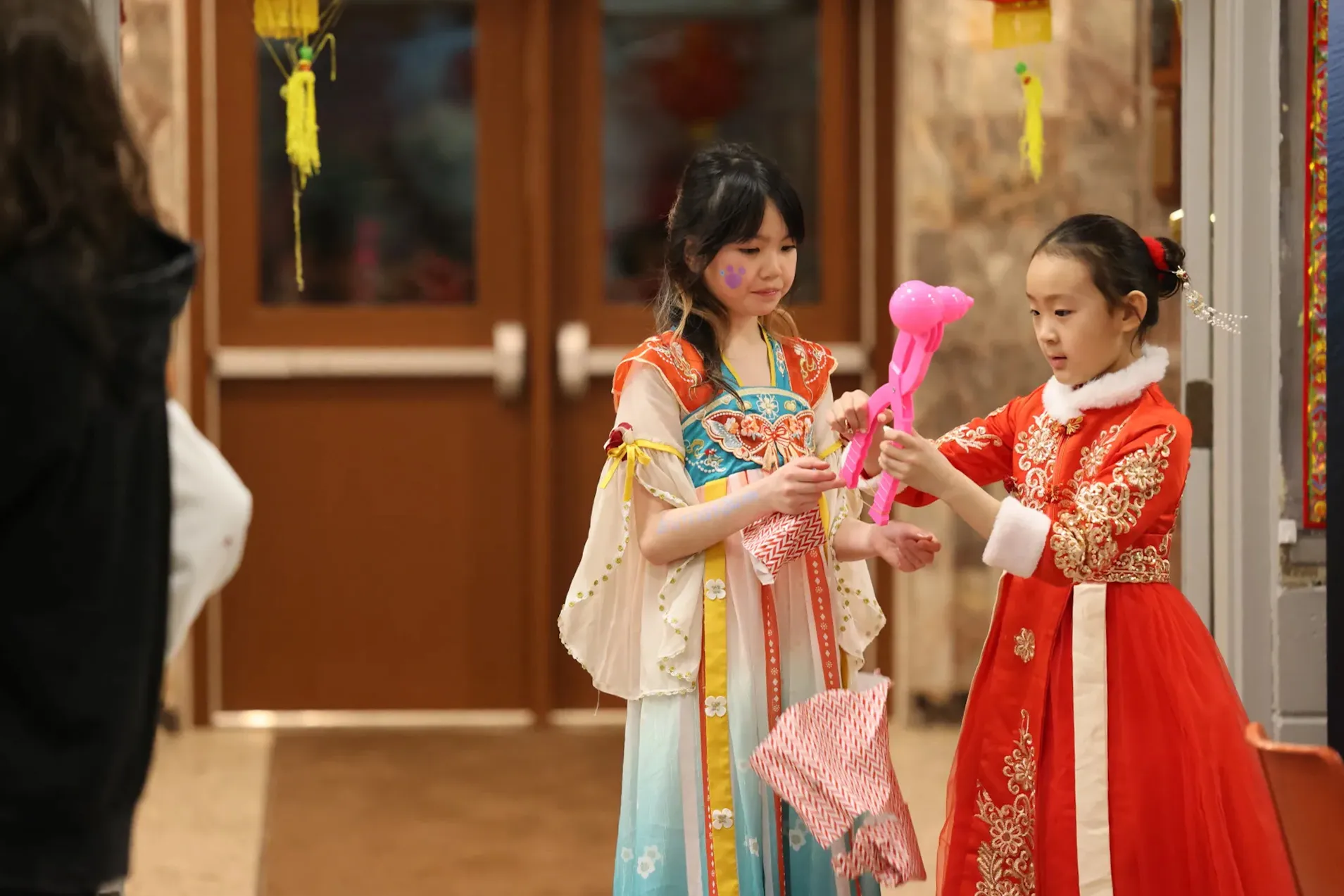 Two girls in traditional Chinese outfits celebrating at a CCAKD Lunar New Year event